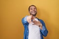 Hispanic man standing over yellow background laughing at you, pointing finger to the camera with hand over body, shame expression Royalty Free Stock Photo