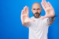 Hispanic man with tattoos standing over blue background doing frame using hands palms and fingers, camera perspective Royalty Free Stock Photo