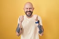 Hispanic man with tattoos standing over yellow background excited for success with arms raised and eyes closed celebrating victory Royalty Free Stock Photo