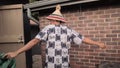 Hispanic man twirling around wearing a traditional african dashiki shirt and mokorotlo hat