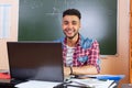 Hispanic Man Using Laptop Computer, Student In University Classroom At Desk Over Chalk Board Royalty Free Stock Photo