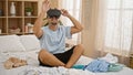 Hispanic man using vr headset in a messy bedroom, portraying technology use in a domestic setting Royalty Free Stock Photo