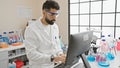 Hispanic man working with computer in a lab full of chemistry equipment Royalty Free Stock Photo