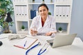 Hispanic mature doctor woman holding pill and glass of water relaxed with serious expression on face Royalty Free Stock Photo