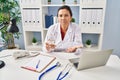 Hispanic mature doctor woman holding pill and glass of water skeptic and nervous, frowning upset because of problem Royalty Free Stock Photo