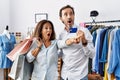 Hispanic middle age couple holding shopping bags and credit card pointing with finger surprised ahead, open mouth amazed Royalty Free Stock Photo