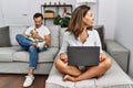 Hispanic middle age couple at home, woman using laptop looking to side, relax profile pose with natural face with confident smile Royalty Free Stock Photo