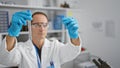 Hispanic middle age man, a serious scientist engrossed in his experiment, securely handles test tubes in his lab, carefully Royalty Free Stock Photo