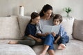 Caring mother reading fascinating book to little kids