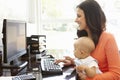 Hispanic mother with baby working in home office