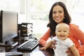 Hispanic mother with baby in working home office Royalty Free Stock Photo