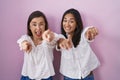 Hispanic mother and daughter together pointing to you and the camera with fingers, smiling positive and cheerful Royalty Free Stock Photo