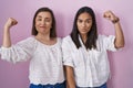 Hispanic mother and daughter together strong person showing arm muscle, confident and proud of power