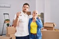 Hispanic mother and son holding keys of new home serious face thinking about question with hand on chin, thoughtful about Royalty Free Stock Photo