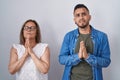 Hispanic mother and son standing together begging and praying with hands together with hope expression on face very emotional and Royalty Free Stock Photo