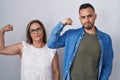 Hispanic mother and son standing together strong person showing arm muscle, confident and proud of power