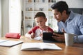 Hispanic pre-teen boy sitting at dining table working with his home school tutor Royalty Free Stock Photo