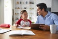 Hispanic pre-teen boy sitting at table working with his home school tutor, smiling at each other Royalty Free Stock Photo