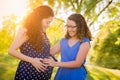 Hispanic Pregnant Mother and Daughter Feeling Belly