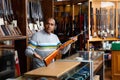 Hispanic salesman showing hunting single-barrel rifle at gun shop