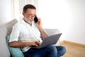 Hispanic Senior Man Talking on Phone Using Laptop At Home Royalty Free Stock Photo