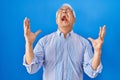 Hispanic senior man wearing glasses celebrating mad and crazy for success with arms raised and closed eyes screaming excited Royalty Free Stock Photo