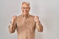 Hispanic senior man wearing glasses excited for success with arms raised and eyes closed celebrating victory smiling Royalty Free Stock Photo