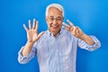 Hispanic senior man wearing glasses showing and pointing up with fingers number eight while smiling confident and happy Royalty Free Stock Photo