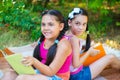 Hispanic sisters reading in summer park