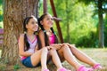 Hispanic sisters sitting under the tree and talking