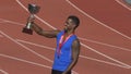 Hispanic sportsman with gold medal on chest holding cup, realizing his victory