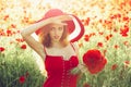Hispanic spring girl with fashionable spanish makeup, rose flower in hair. Girl in field of poppy seed in retro hat. Royalty Free Stock Photo