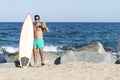 Handsome surfer man with sunglasses holding a surfer board at sea shore Royalty Free Stock Photo