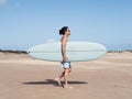 Hispanic surfer walking on the sand holding his surfboard Royalty Free Stock Photo