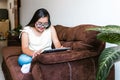 Hispanic teen girl with down syndrome using a tablet while sitting on the sofa at home, in disability concept in Latin America Royalty Free Stock Photo
