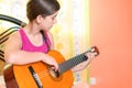 Hispanic teenage girl playing guitar at home