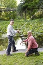 Hispanic teenager and father fishing in pond Royalty Free Stock Photo
