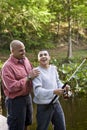 Hispanic teenager and father fishing in pond Royalty Free Stock Photo