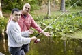 Hispanic teenager and father fishing in pond Royalty Free Stock Photo