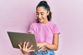 Hispanic teenager girl with dental braces holding and using computer laptop looking positive and happy standing and smiling with a Royalty Free Stock Photo