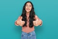 Hispanic teenager girl with dental braces wearing casual clothes approving doing positive gesture with hand, thumbs up smiling and Royalty Free Stock Photo