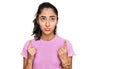 Hispanic teenager girl with dental braces wearing casual clothes pointing up looking sad and upset, indicating direction with