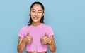 Hispanic teenager girl with dental braces wearing casual clothes success sign doing positive gesture with hand, thumbs up smiling Royalty Free Stock Photo