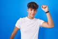 Hispanic teenager standing over blue background dancing happy and cheerful, smiling moving casual and confident listening to music Royalty Free Stock Photo