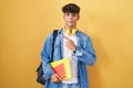 Hispanic teenager wearing student backpack and holding books cheerful with a smile on face pointing with hand and finger up to the Royalty Free Stock Photo