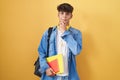 Hispanic teenager wearing student backpack and holding books looking confident at the camera smiling with crossed arms and hand Royalty Free Stock Photo