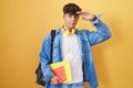 Hispanic teenager wearing student backpack and holding books very happy and smiling looking far away with hand over head Royalty Free Stock Photo