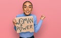 Hispanic transgender man wearing make up and long hair holding we need a change banner screaming proud, celebrating victory and