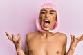 Hispanic transgender man wearing make up and pink wig crazy and mad shouting and yelling with aggressive expression and arms