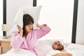 Hispanic woman angry with pillow on his ears while man snoring on the bed Royalty Free Stock Photo